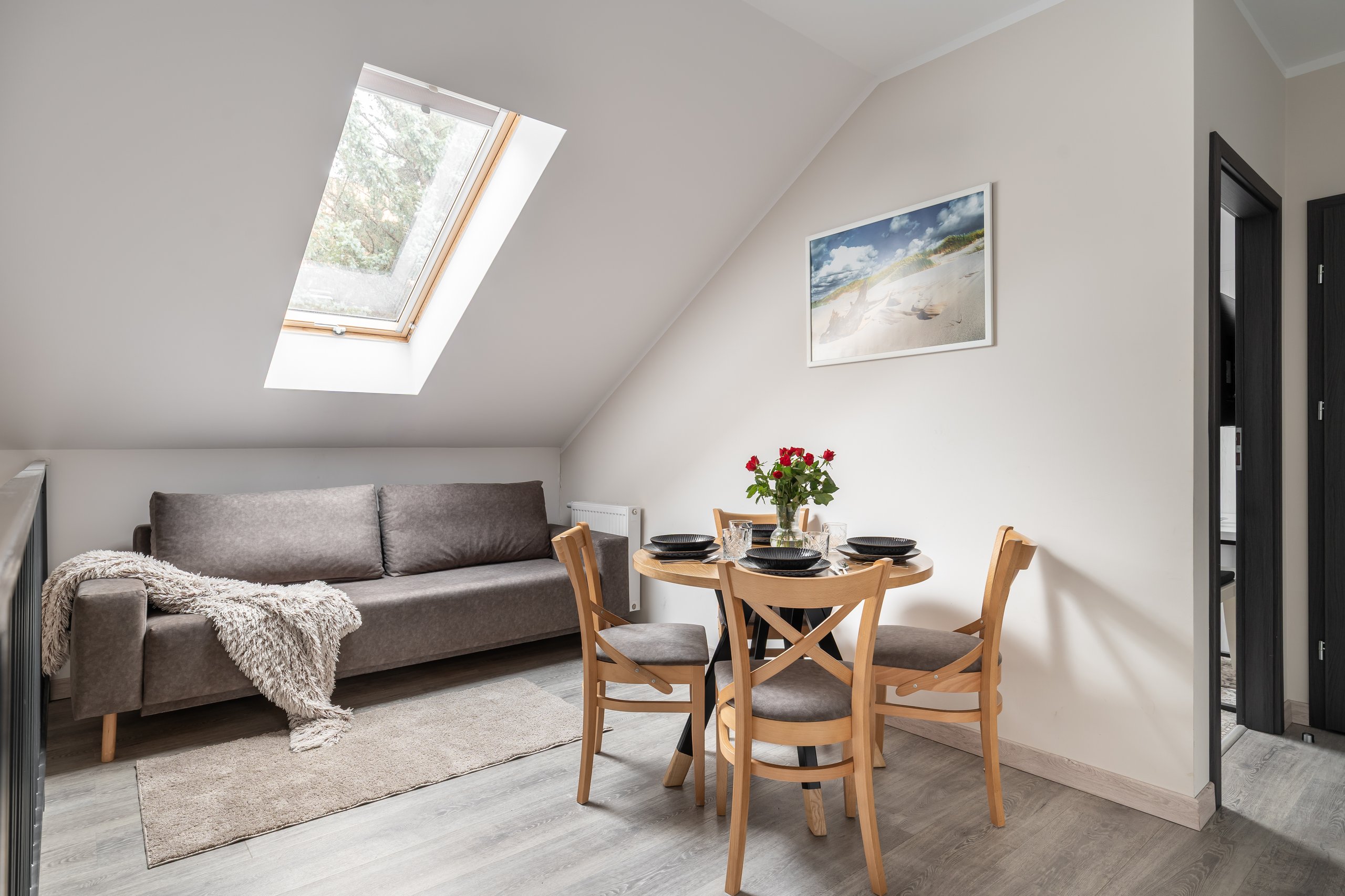 Apartment Maisonette Lux in der Residenz AMBRE in Łeba – Wohnbereich im Dachgeschoss mit Sofa, Tisch und Dachfenster