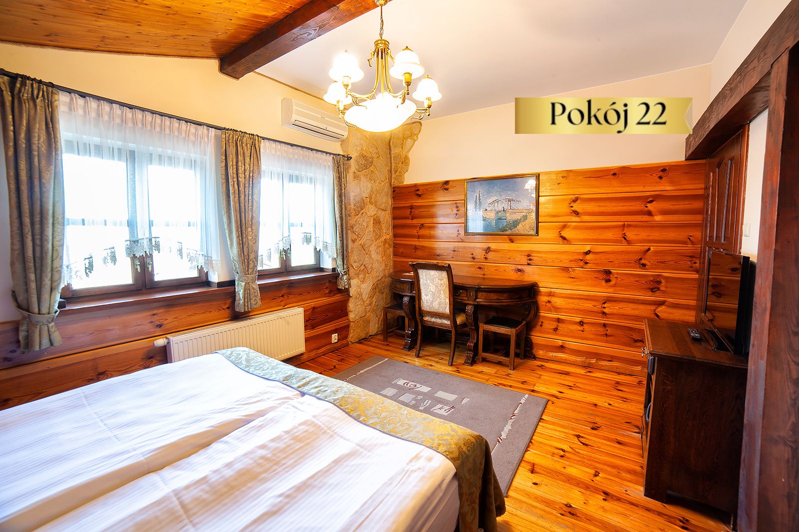 Pokój Standard nr 22 w Dworku Wapionka – łóżko, drewniane ściany i biurko pod oknem