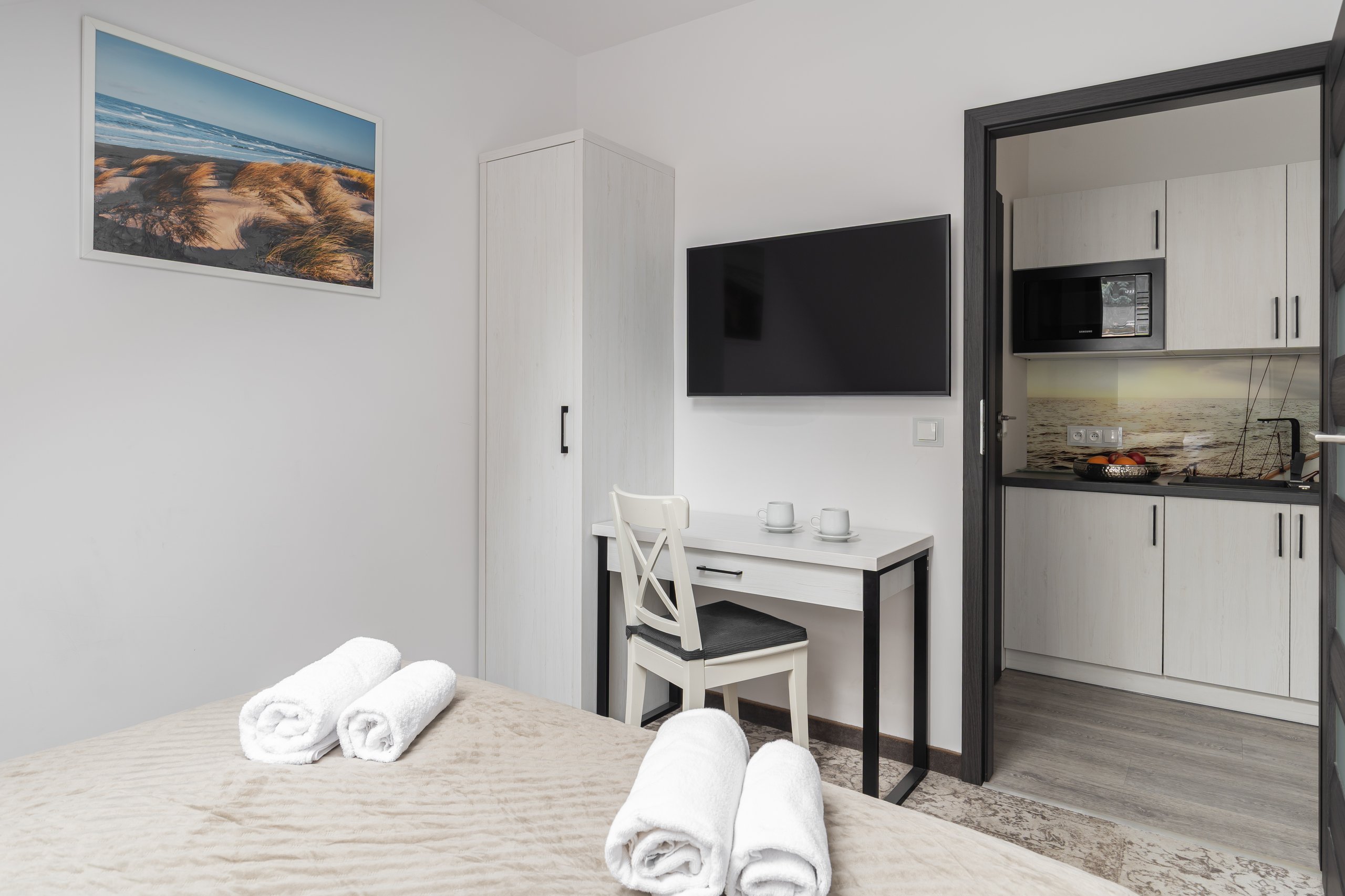 Apartment Maisonette Lux in der Residenz AMBRE in Łeba – Schlafzimmer mit Fernseher, Schreibtisch und Blick auf die Kochnische