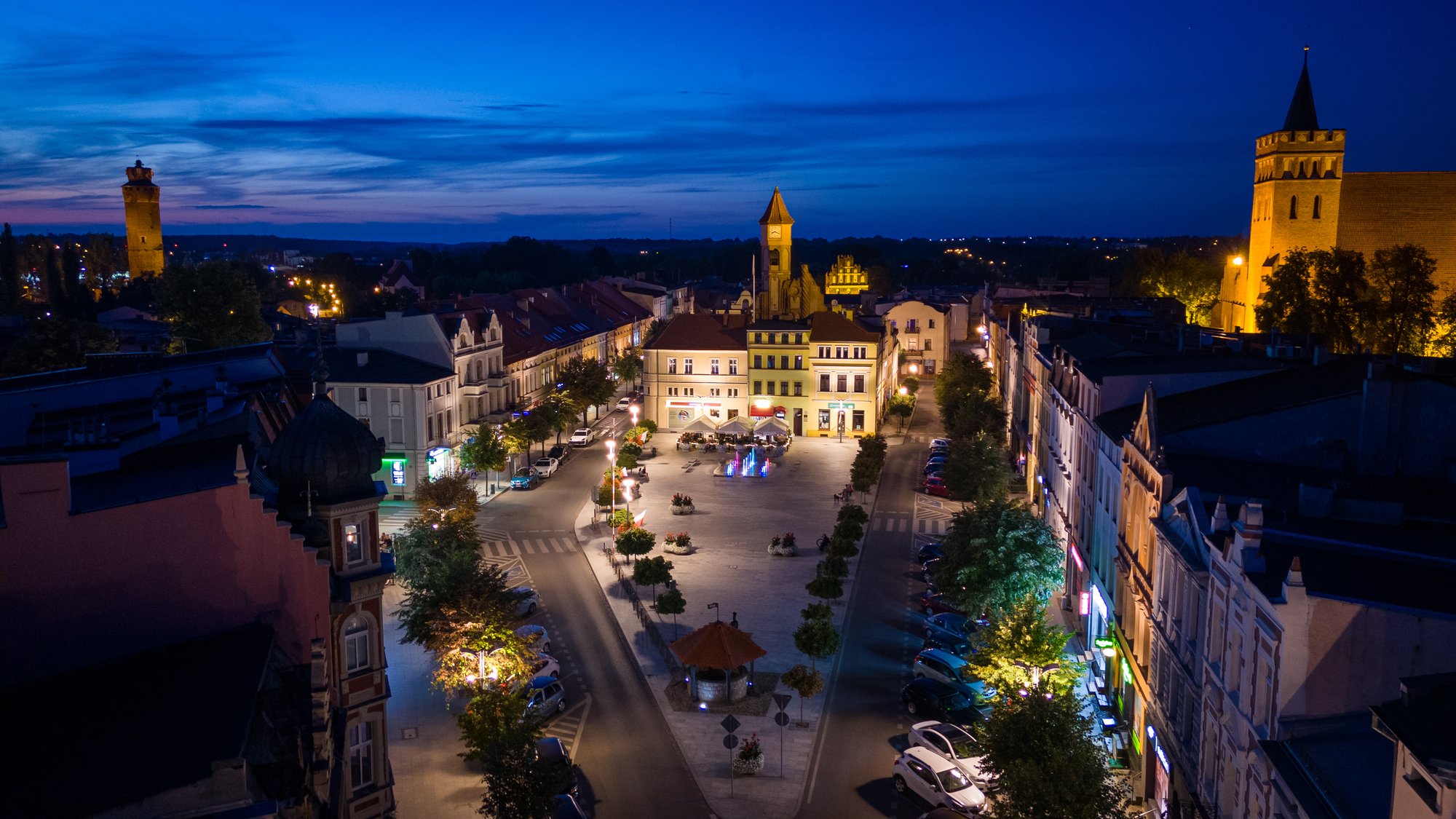 Rynek w Brodnicy nocą, widok z lotu ptaka na oświetlone kamienice i wieże. Fot. Wiater Media
