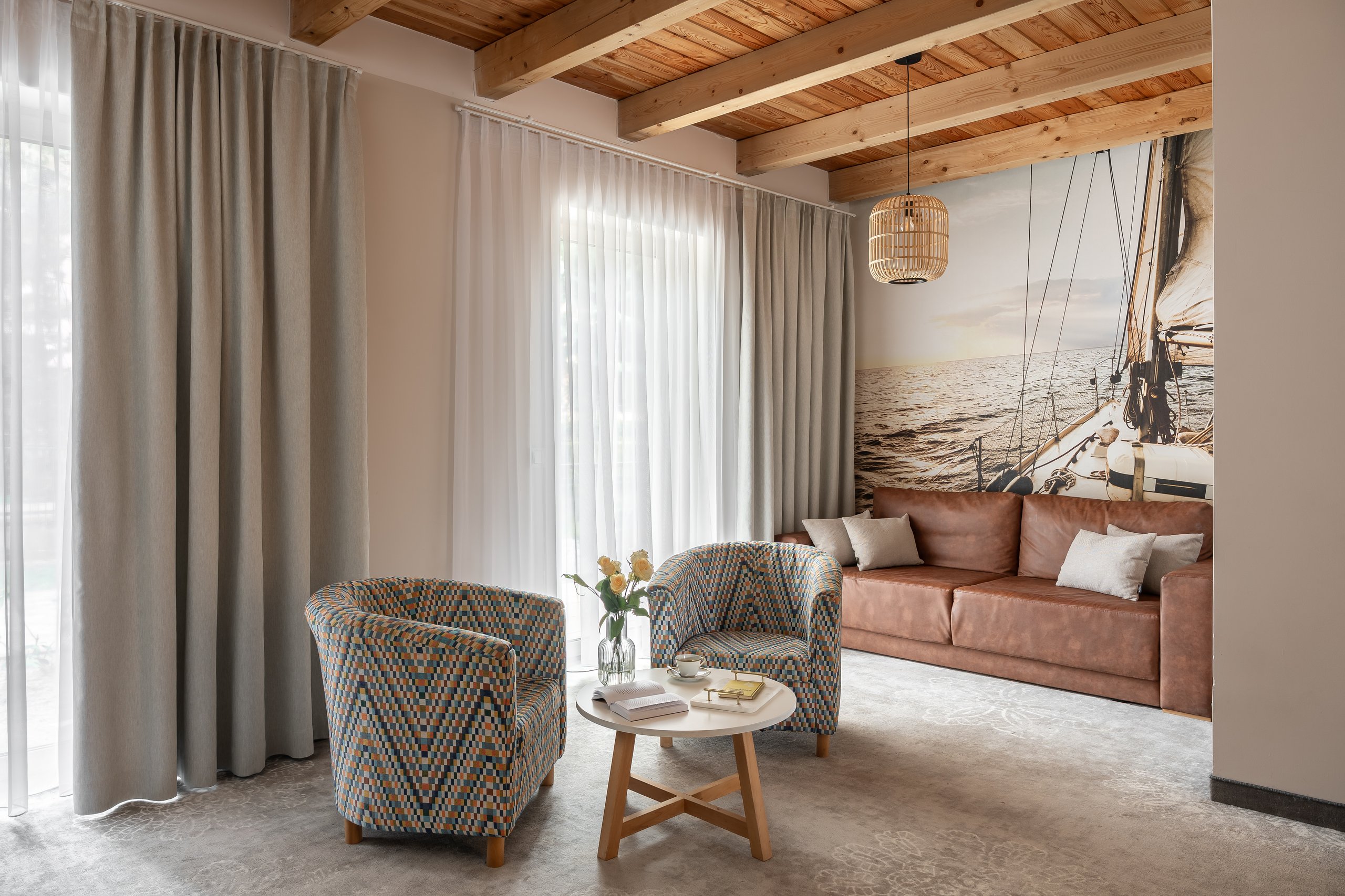 Apartment Maisonette Lux in der Residenz AMBRE in Łeba – Wohnzimmer mit Holzdecke, Fototapete mit Segelboot und Sesseln
