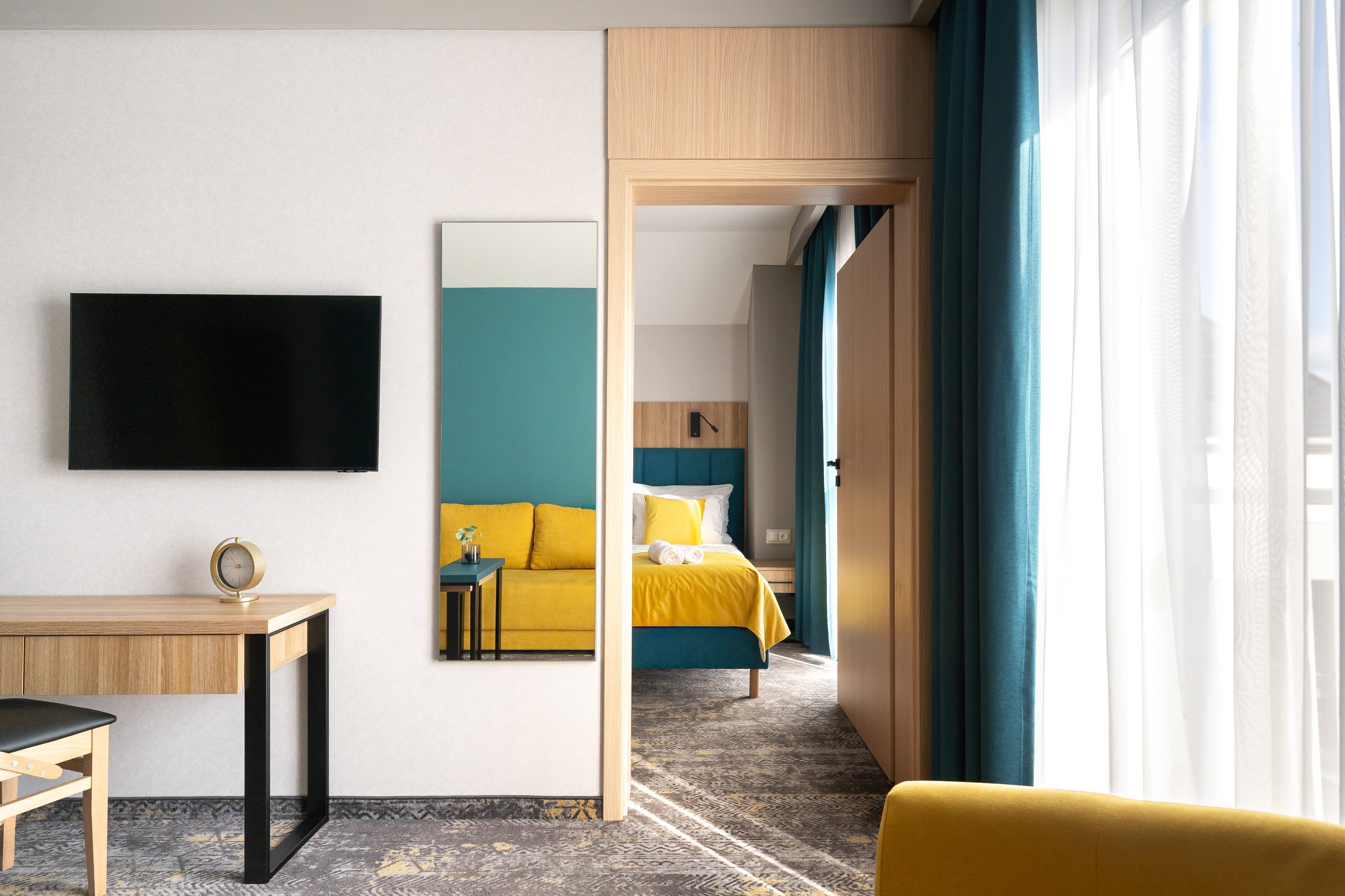 Premium-Suite-Zimmer in der Residenz AMBRE in Łeba mit Fernseher und Schreibtisch und im Hintergrund einem separaten Schlafzimmer.