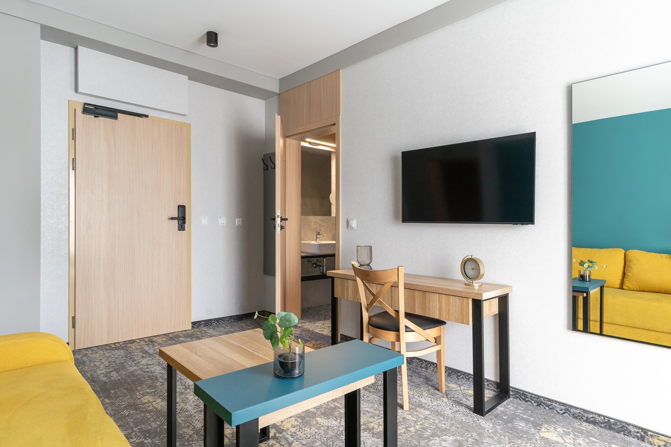 Premium-Suite-Zimmer in der Residenz AMBRE in Łeba mit Wohnbereich, Fernseher, Schreibtisch, Spiegel und einem Tisch.