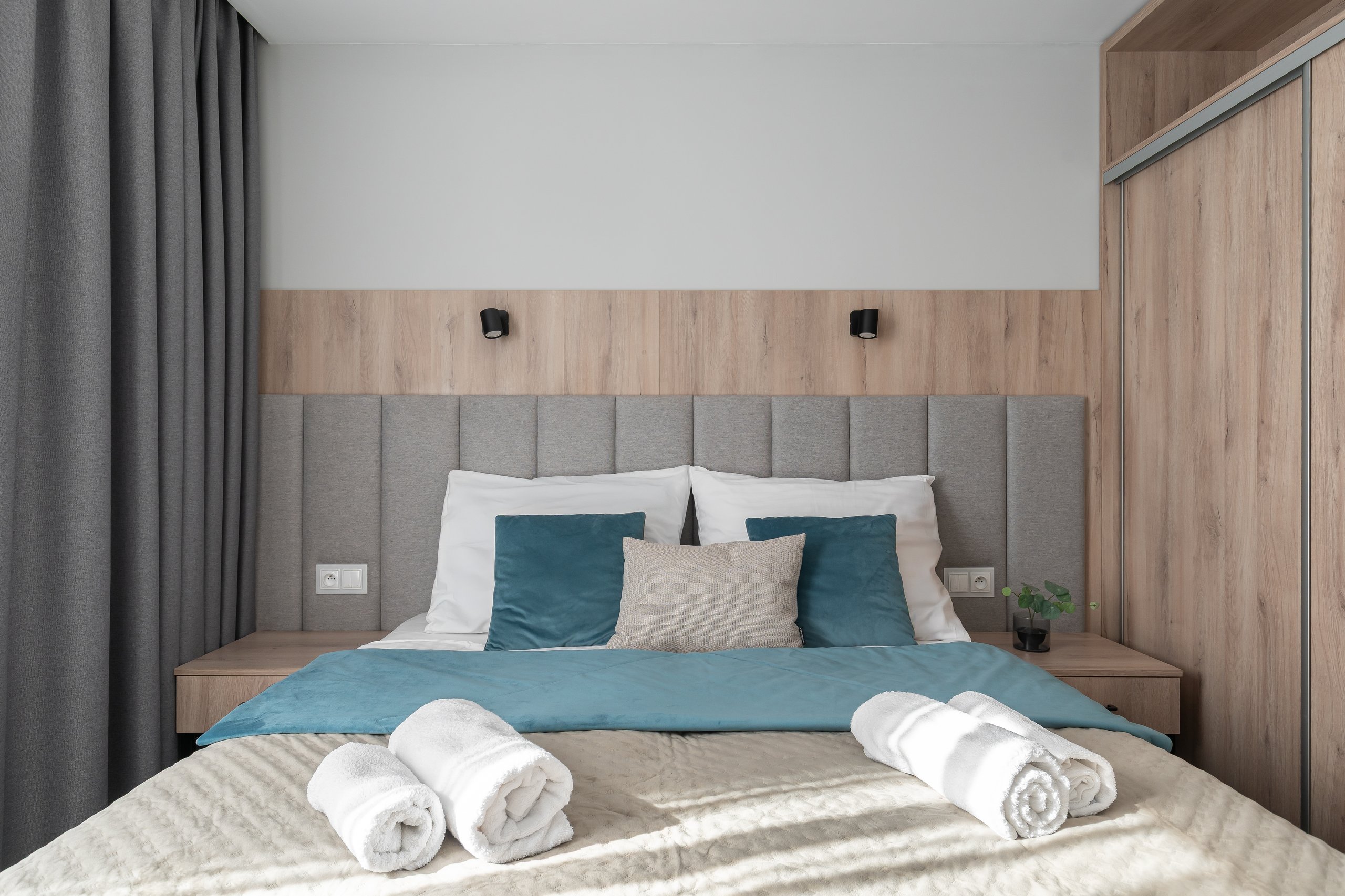 Suite-Zimmer in der Residenz AMBRE in Łeba mit einem Bett mit grauem, gepolstertem Kopfteil und Lampen.