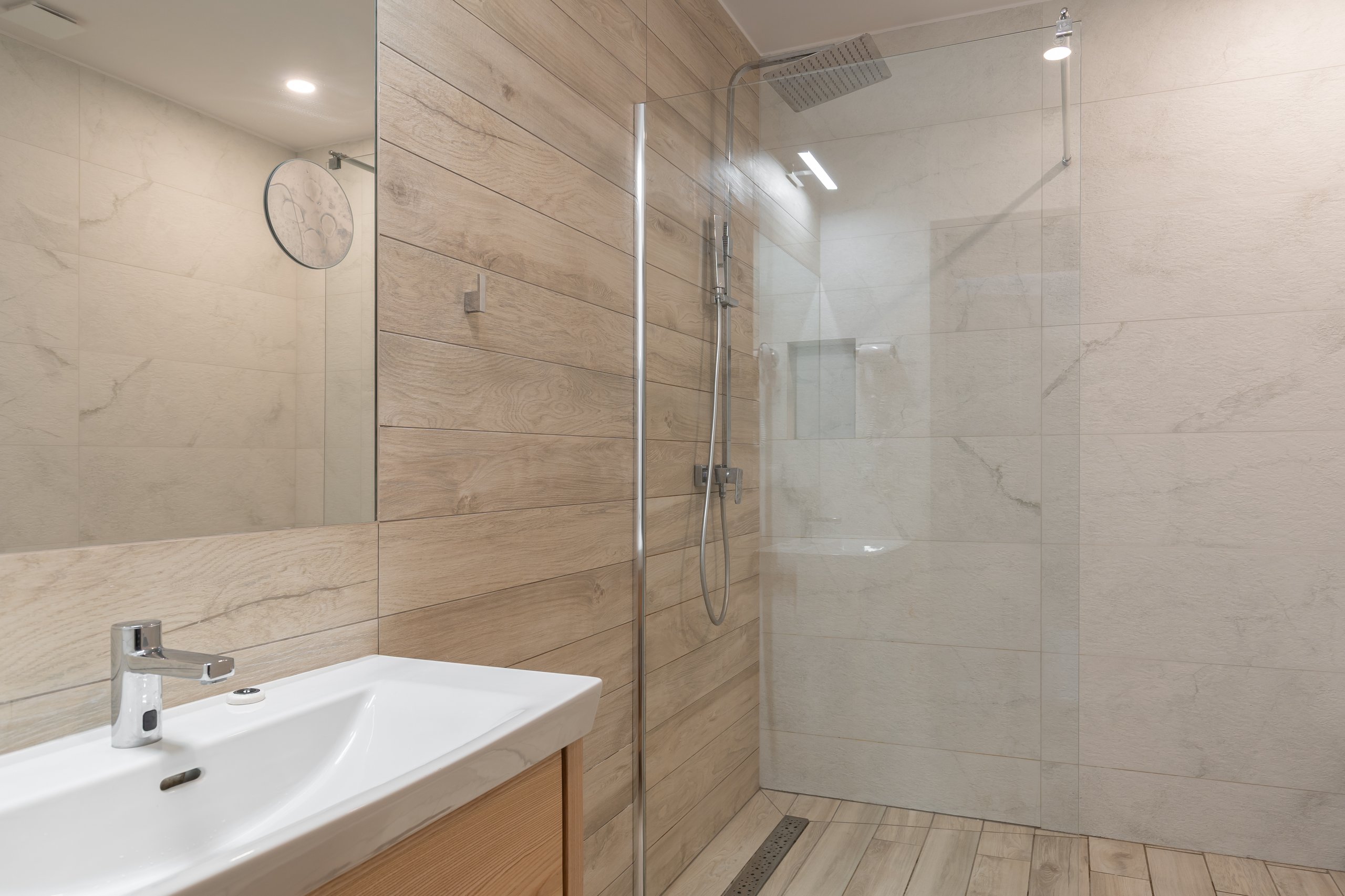 Badezimmer im Apartment in der Residenz AMBRE in Łeba – Dusche mit Regenbrause hinter einer Glaswand.