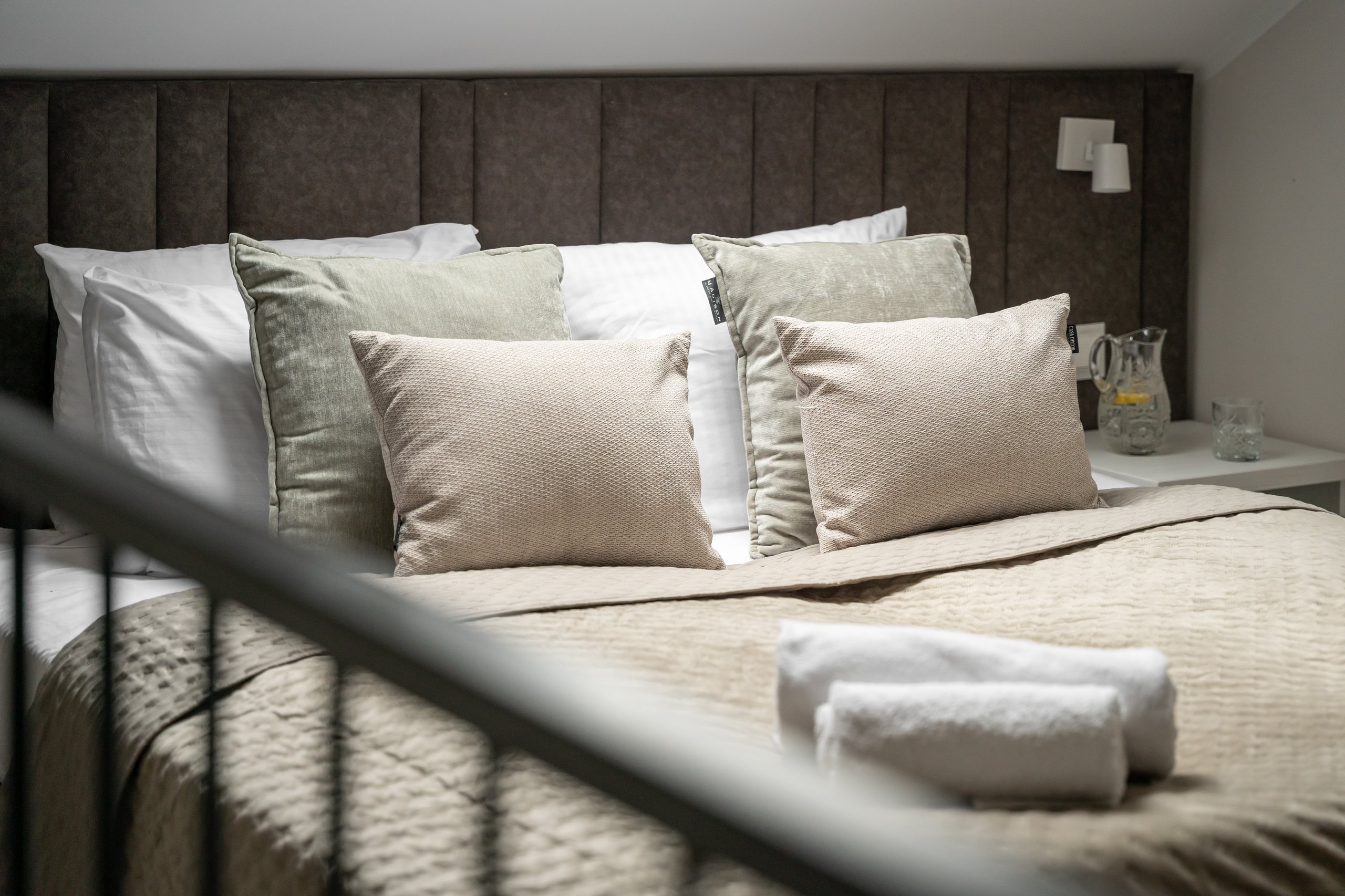 Apartment Maisonette Comfort in der Residenz AMBRE in Łeba – Bett mit gestepptem Kopfteil und Kissen.