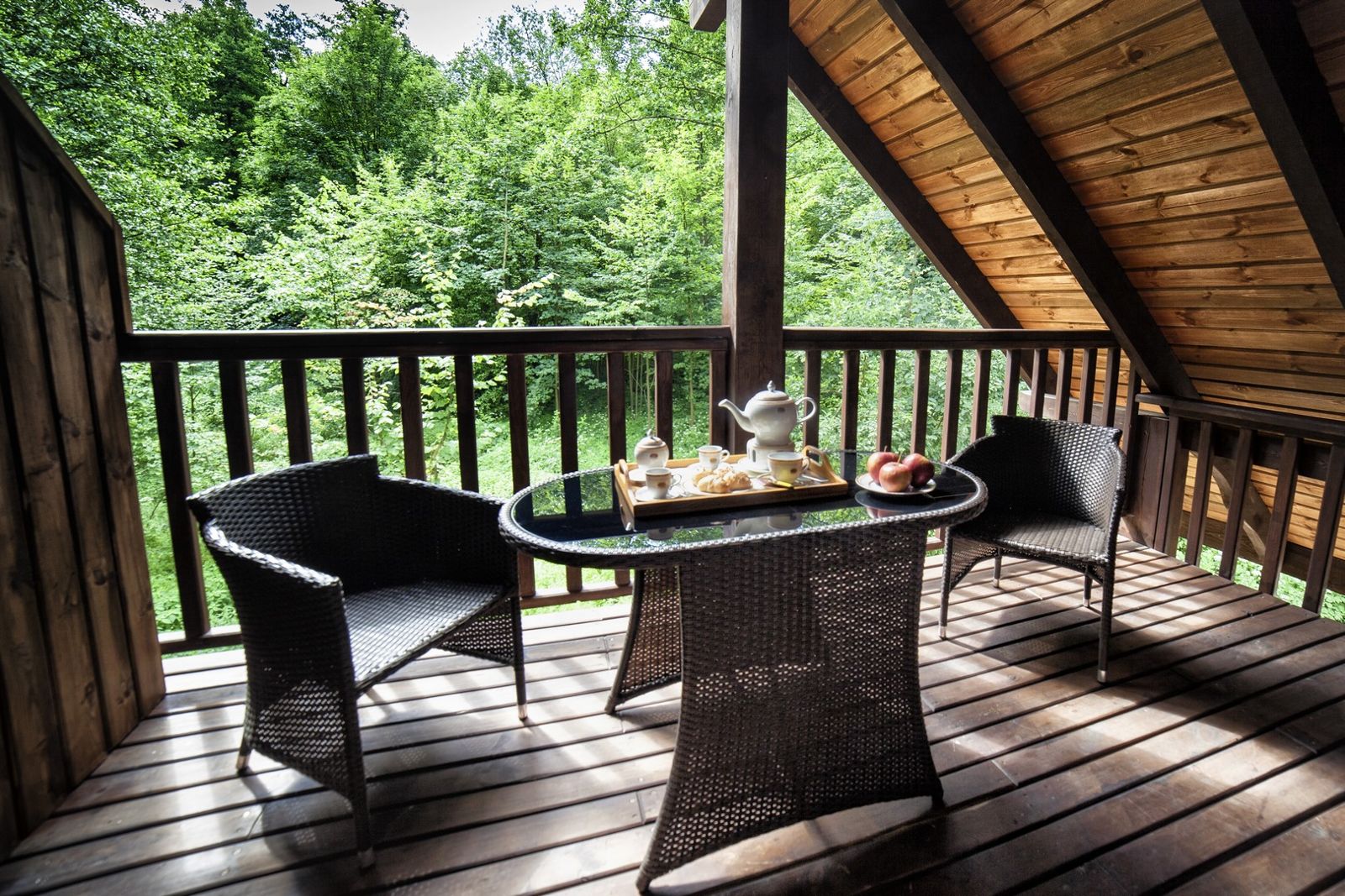 Balkon pokoju Comfort z wiklinowymi meblami i widokiem na las