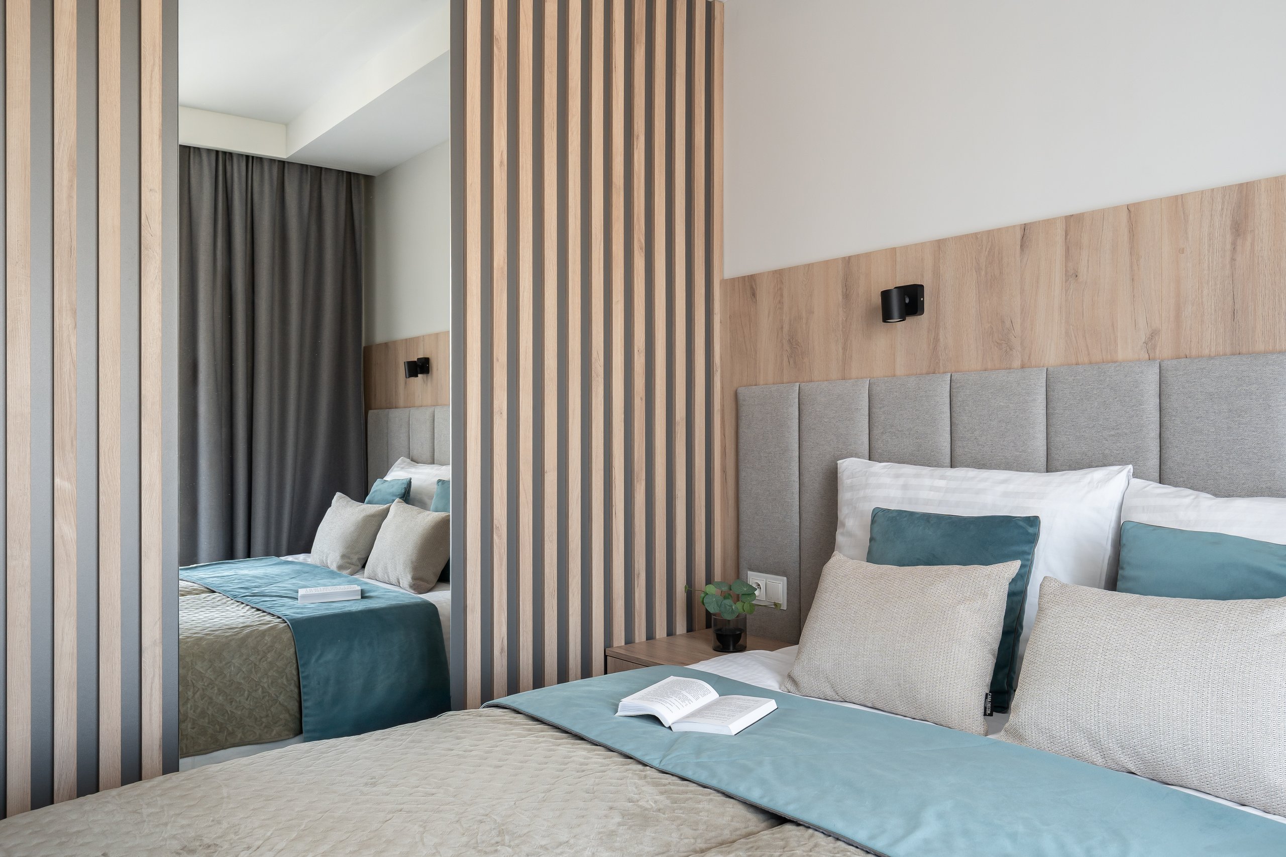 Comfort-Zimmer in der Residenz AMBRE in Łeba – Bett hinter einer hölzernen Lamellenwand und einem Spiegel.