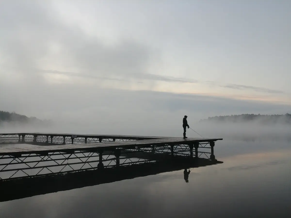 Wędkarz na pomoście o świcie nad jeziorem Bachotek