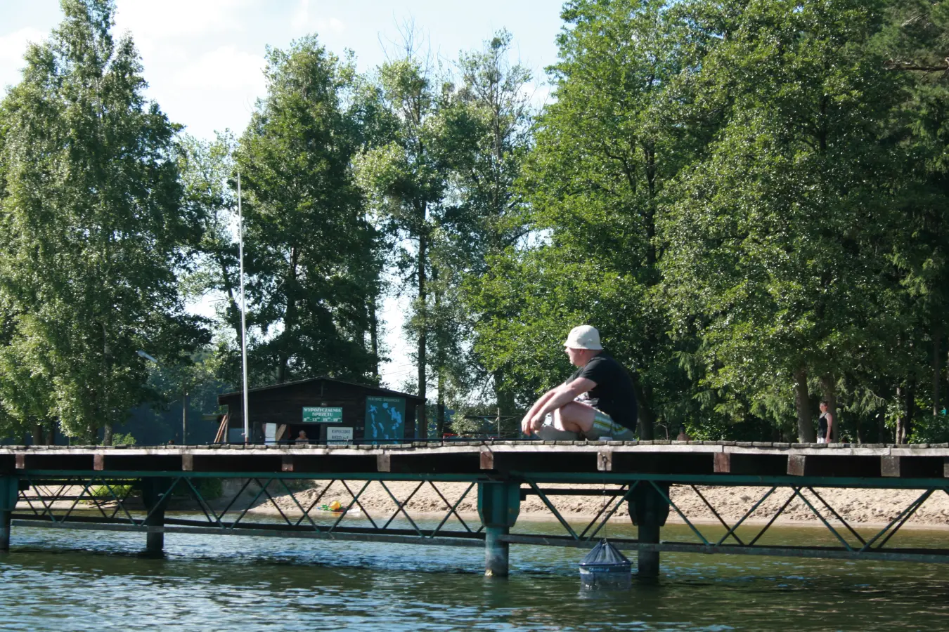 Osoba odpoczywająca na pomoście nad jeziorem Bachotek