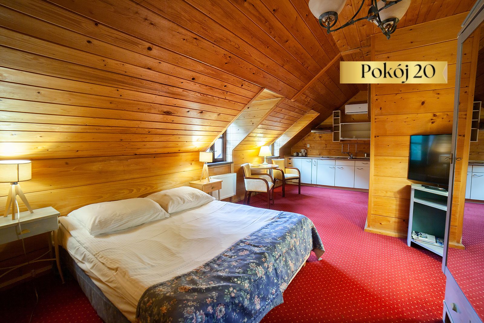 Pokój Standard Plus nr 20 na poddaszu – łóżko, telewizor i czerwona wykładzina