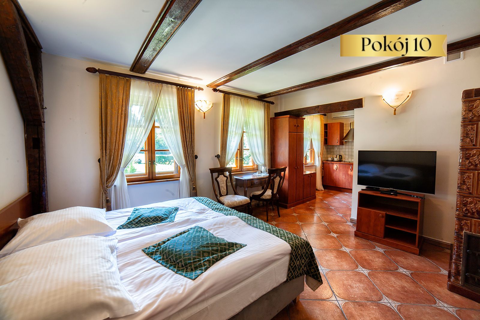 Pokój Standard Plus nr 10 w Dworku Wapionka – łóżko, telewizor i drewniane belki