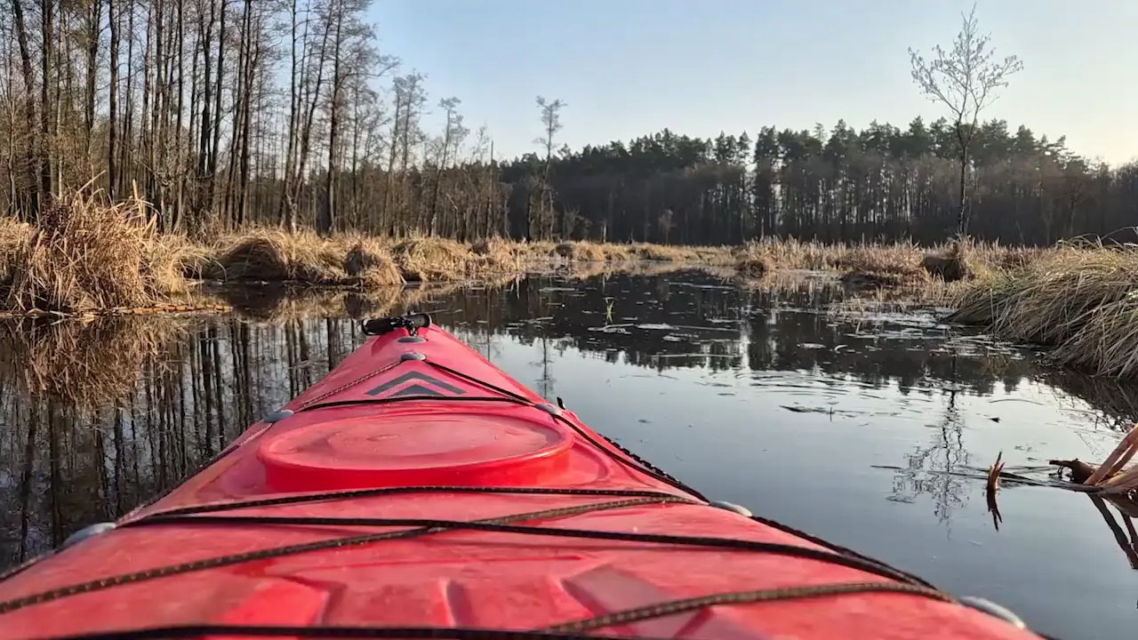 Dziób czerwonego kajaka na spokojnym jeziorze
