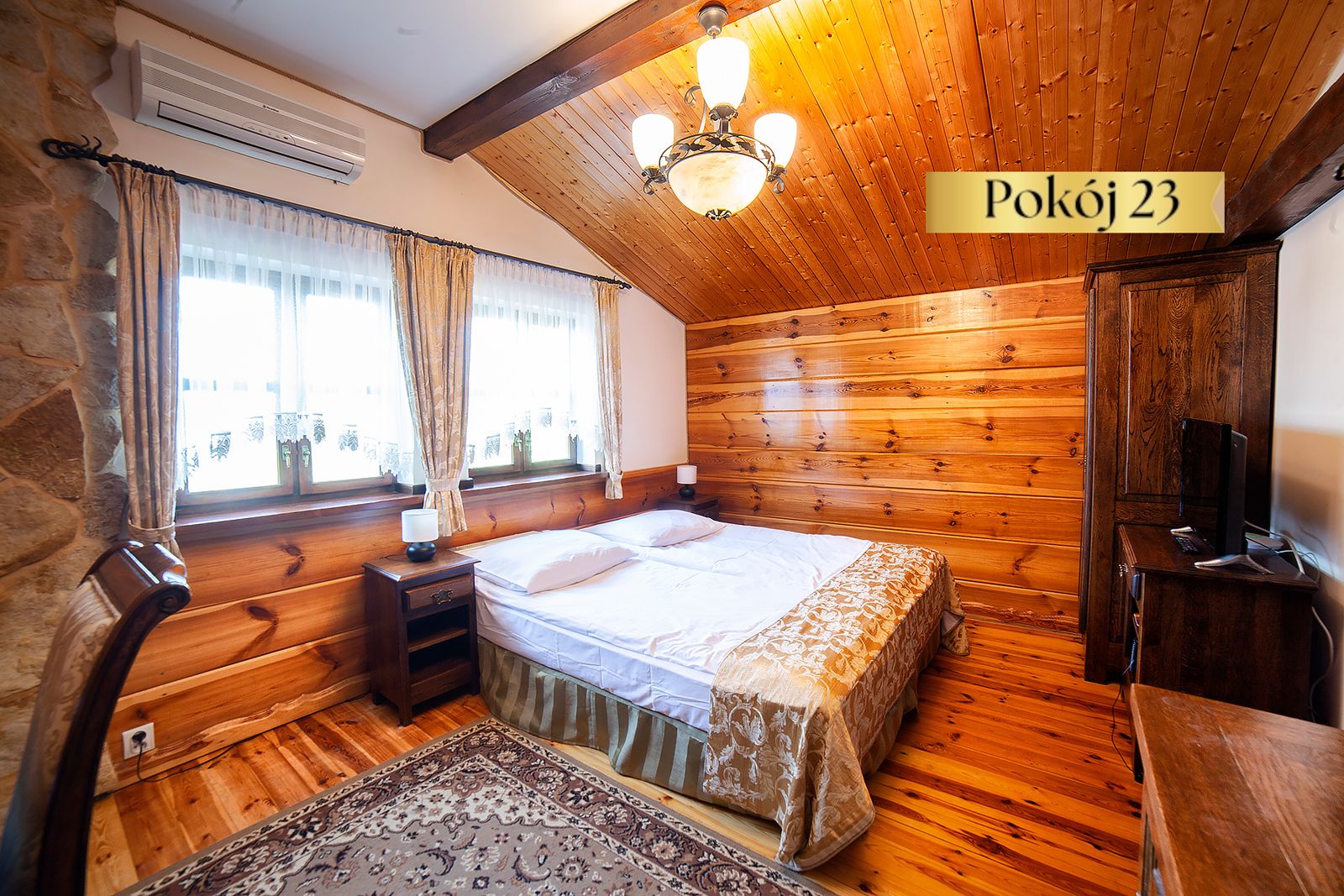 Pokój Standard nr 23 – podwójne łóżko, drewniana boazeria i dywan na podłodze