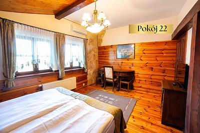 Pokój Standard nr 22 w Dworku Wapionka – łóżko, drewniane ściany i biurko pod oknem