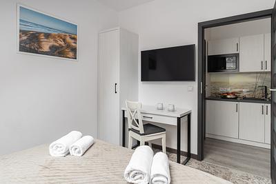 Apartment Maisonette Lux in der Residenz AMBRE in Łeba – Schlafzimmer mit Fernseher, Schreibtisch und Blick auf die Kochnische