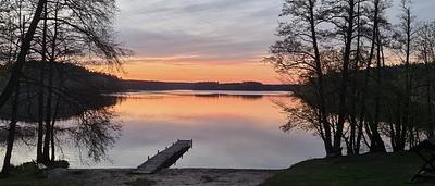 Zachód słońca nad jeziorem Sosno, pomost i drzewa na brzegu