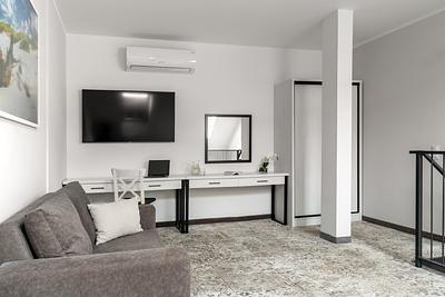 Apartment Maisonette Comfort Plus in der Residenz AMBRE in Łeba – Schreibtisch mit Spiegel, Fernseher und graues Sofa auf der Empore