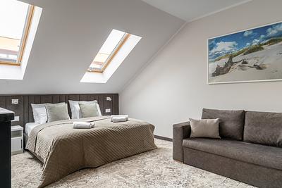Apartment Maisonette Comfort Plus in der Residenz AMBRE in Łeba – Schlafzimmer im Dachgeschoss mit Bett und Sofa