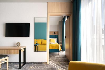 Premium-Suite-Zimmer in der Residenz AMBRE in Łeba mit Fernseher und Schreibtisch und im Hintergrund einem separaten Schlafzimmer.