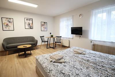 A room with a large bed, a sofa, and a small seating area with a table in Hajduczek