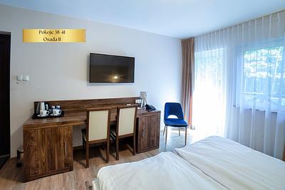 The Comfort Plus room in Osada II has a desk with chairs and a window overlooking greenery.