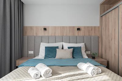 Suite-Zimmer in der Residenz AMBRE in Łeba mit einem Bett mit grauem, gepolstertem Kopfteil und Lampen.