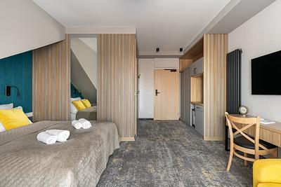 Superior-Zimmer in der Residenz AMBRE in Łeba mit geräumigem Interieur, Bett, Holzwand und Schreibtisch.
