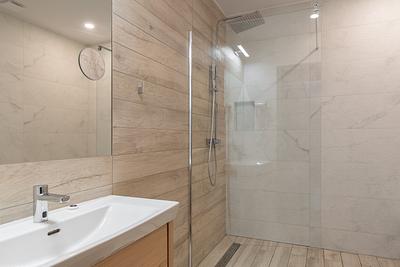 Badezimmer im Apartment in der Residenz AMBRE in Łeba – Dusche mit Regenbrause hinter einer Glaswand.