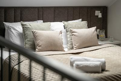 Apartment Maisonette Comfort in der Residenz AMBRE in Łeba – Bett mit gestepptem Kopfteil und Kissen.