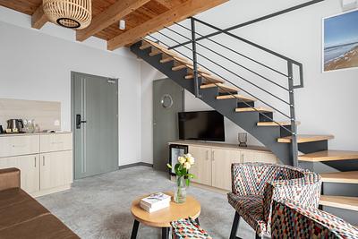 Apartment Maisonette Comfort in der Residenz AMBRE in Łeba – Treppe zum Mezzanin, Fernseher und Kaffeebereich.