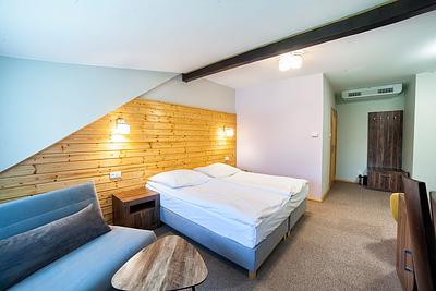 Pokój Comfort Superior – łóżko, rozkładany fotel i drewniana ściana