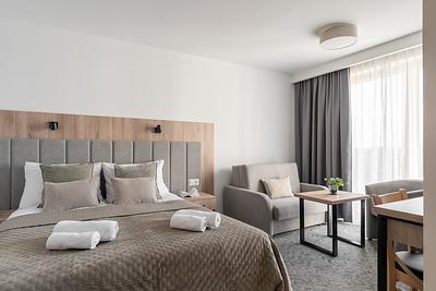 Superior-Junior-Zimmer in der Residenz AMBRE in Łeba mit Bett, Sessel und Tisch am großen Fenster.