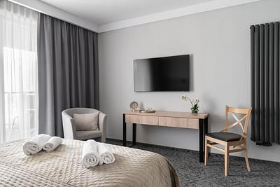 Comfort-Plus-Zimmer in der Residenz AMBRE in Łeba – Bett, Sessel, Schreibtisch und Fernseher am Fenster.