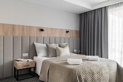 Comfort-Plus-Zimmer in der Residenz AMBRE in Łeba – Bett mit beiger Tagesdecke und Kissen am Fenster.