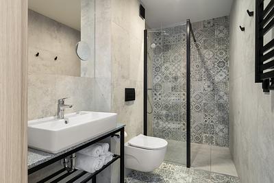 Badezimmer im Zimmer der Residenz AMBRE in Łeba – Dusche hinter einer Glaswand, Waschbecken und wandhängende Toilette.