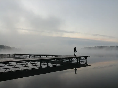 Wędkarz na pomoście o świcie nad jeziorem Bachotek