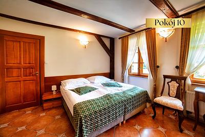 Pokój Standard Plus nr 10 – łóżko z zieloną narzutą i stylowe krzesło