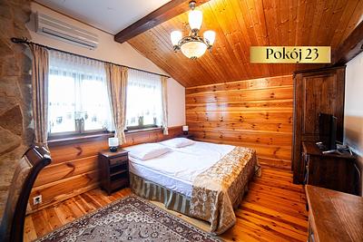 Pokój Standard nr 23 – podwójne łóżko, drewniana boazeria i dywan na podłodze
