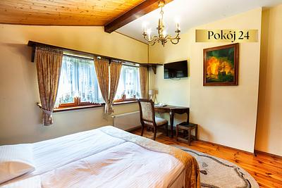 Pokój Standard nr 24 – łóżko, stolik z krzesłami i obraz na ścianie